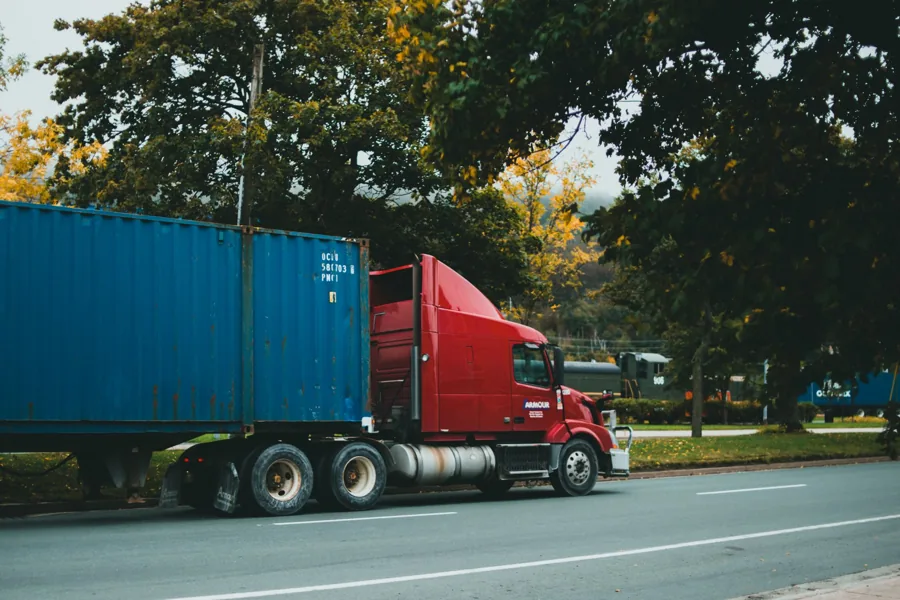 Caminhão transportando contêiner azul em rodovia